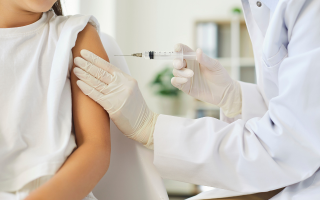 Une personne se prépare à être vaccinée par un professionnel de santé qui porte des gants et tient une piqûre. La Semaine Européenne de la Vaccination aura lieu du 27 avril au 3 mai 2026.